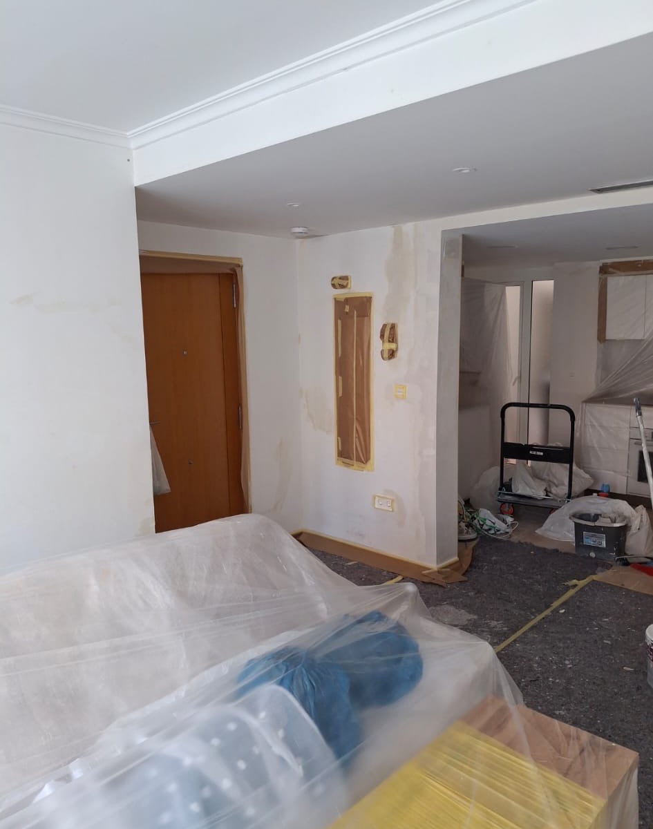 Living area before repaint with furniture protected and repair marks visible.