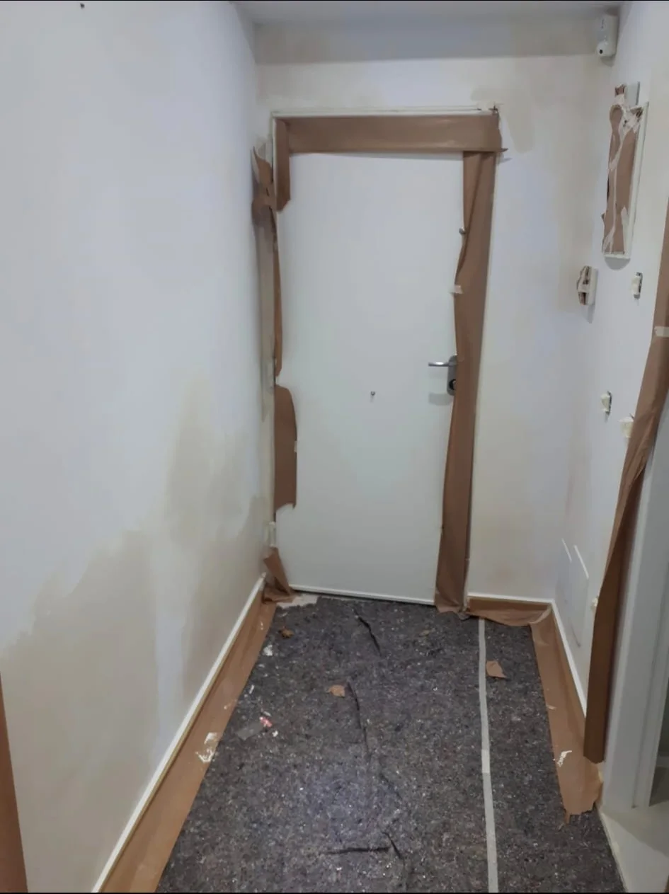 Interior hallway during preparation with masking and repaired surfaces.